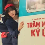 Cảnh phim Trăm Mảnh Ký Ức – Hai nhân vật chính cười rạng rỡ trước xe buýt trong bối cảnh hoài niệm thập niên 1980.