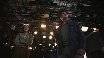 Cảnh phim Mouse: Kẻ Săn Mồi – hai nhân vật chính đang điều tra trong phòng quay truyền hình, ánh sáng mạnh và không khí căng thẳng.