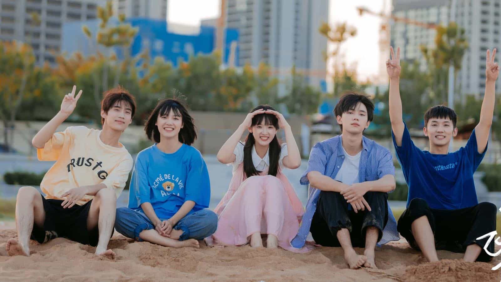 Nhóm bạn trẻ ngồi trên bãi cát, tạo dáng vui vẻ trong phim Khi Anh Chạy Về Phía Em