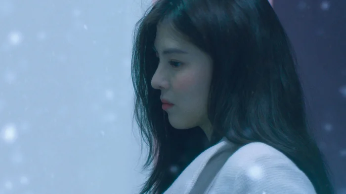 Cảnh nhân vật nữ chính trong phim Đêm Tình Bão Tuyết – Heavy Snow nhìn nghiêng giữa khung cảnh tuyết rơi, ánh mắt trầm buồn.